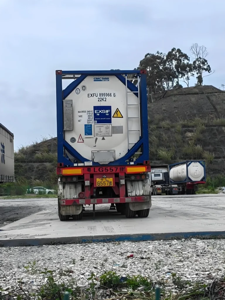 A blue-framed ISO tank container with CIMC TANK branding, equipped with IoT sensors and labeled EXFU 895966 6 22K2, being transported on a heavy-duty trailer for oversized cargo logistics.