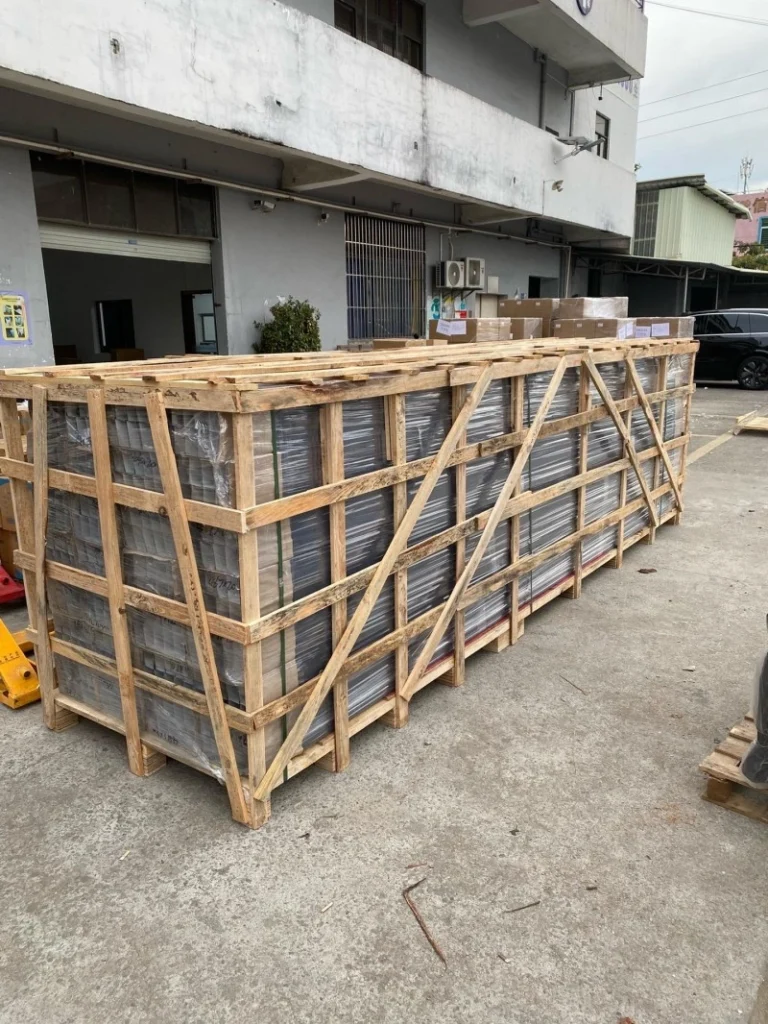 Large wooden crate with visible structural bracing and plastic-wrapped industrial equipment inside, ready for international shipping under ISPM 15 standards