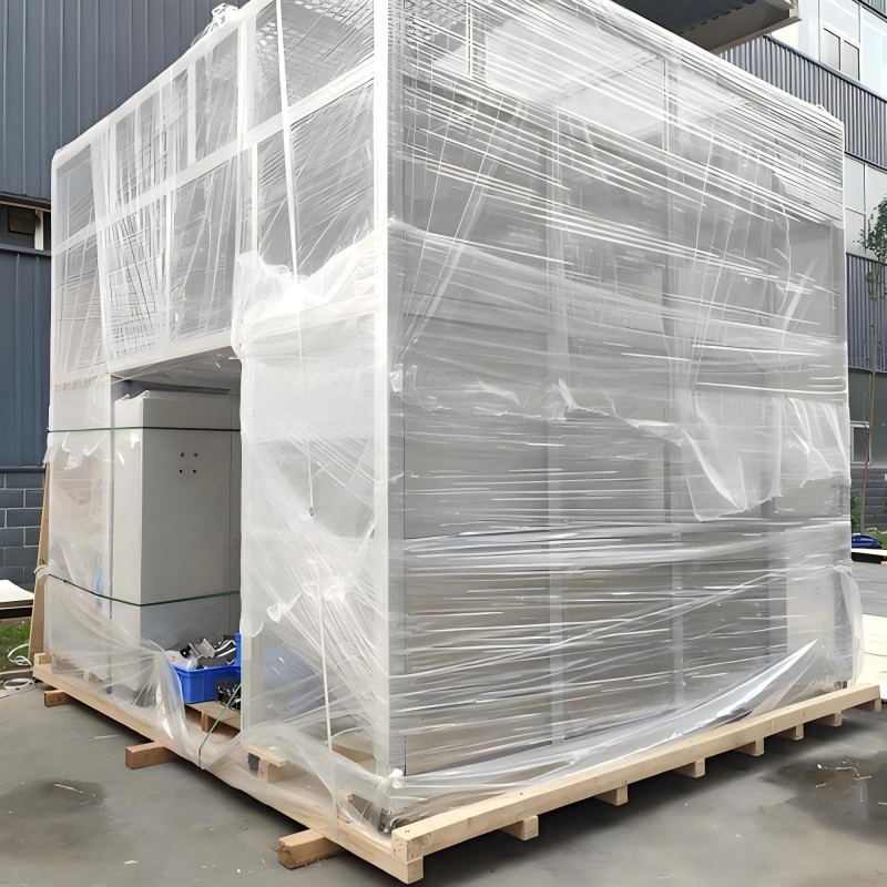 Large manufacturing equipment tightly wrapped in transparent plastic stretch film on a wooden pallet, providing a cost-effective barrier against dust and minor moisture for domestic transport or short-term storage.