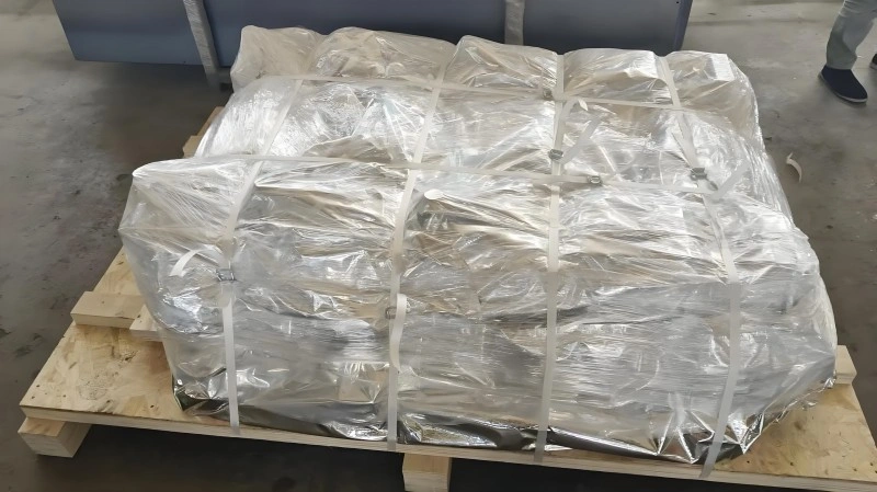 Large industrial equipment wrapped in clear vacuum plastic film on a wooden pallet, preventing moisture damage during ocean freight transport.