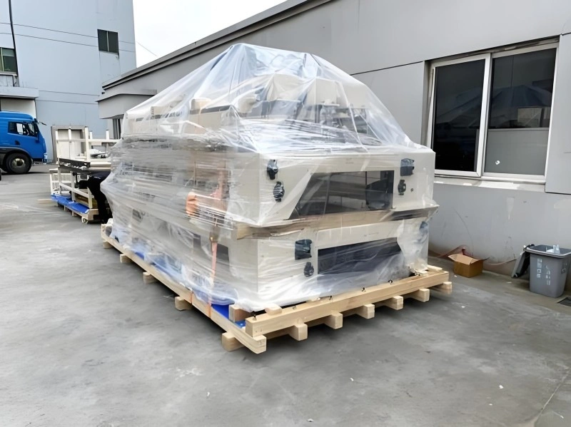 Large industrial machine wrapped in transparent plastic film on a wooden pallet, prepared for moisture and dust protection during ocean freight shipping.