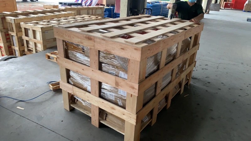 Workers assembling a tall wooden crate with multiple horizontal beams inside a warehouse, demonstrating professional packaging solutions for fragile industrial equipment.