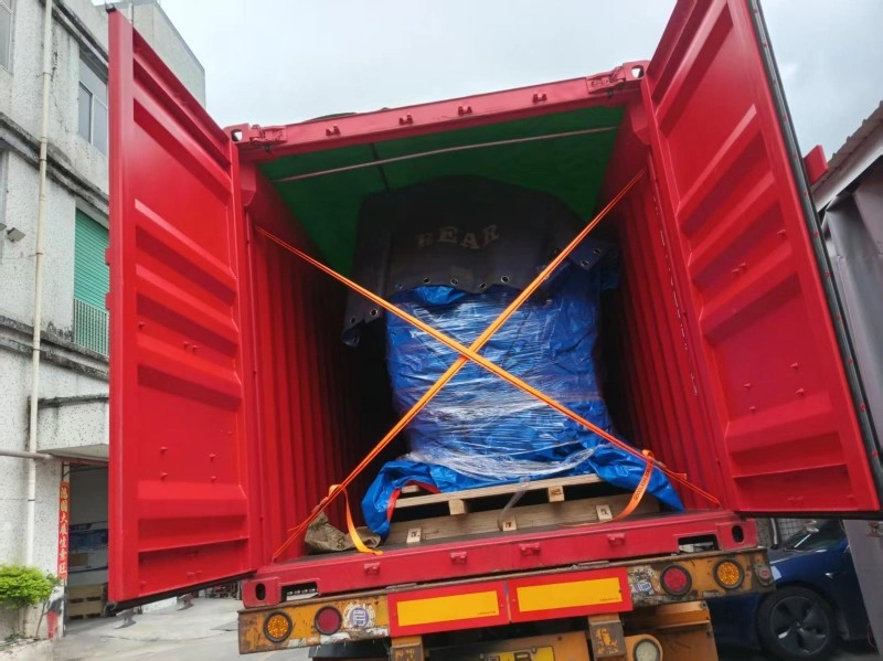View inside an open red shipping container showing a palletized machine wrapped in blue plastic and secured with cross-patterned orange tension straps, illustrating internal load stability for logistics safety.