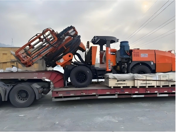 Specialized flatbed transport loading an orange hydraulic mining drilling rig, demonstrating secure handling for oversized OOG cargo logistics
