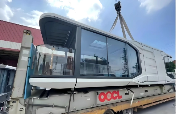 A space capsule cabin being carefully positioned onto a Flat Rack container for ocean freight, emphasizing the specialized equipment used for oversized cargo