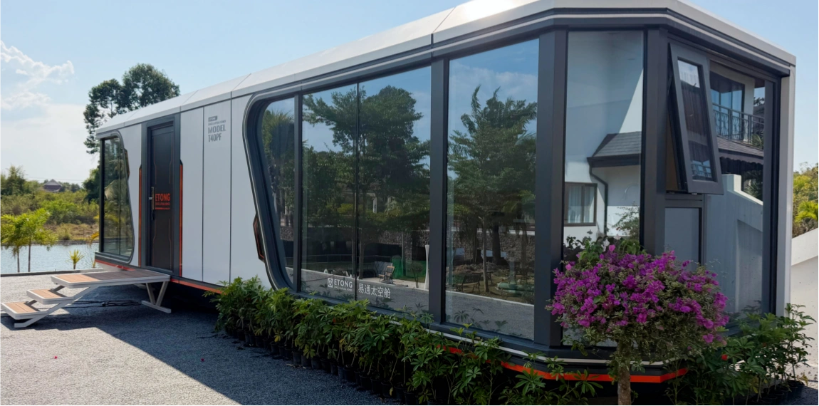 A sleek, modern space capsule cabin with large glass windows, set in a scenic outdoor location, showcasing its design for glamping and vacation rentals