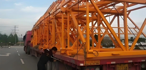 Transport crew inspecting the lashing and stability of oversized yellow steel structures on a flatbed trailer to ensure safe transit compliance.