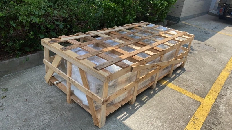 A large wooden crate with a slatted top and reinforced base sitting on concrete outdoors, showcasing custom industrial packaging design for heavy cargo protection.