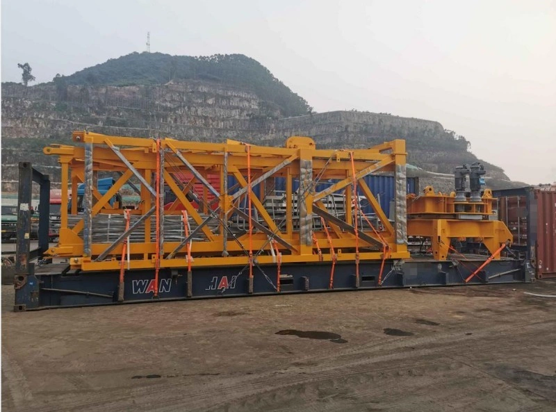A long yellow steel truss structure is positioned on a flat rack container in an outdoor yard, demonstrating specialized loading techniques for out-of-gauge project cargo.
