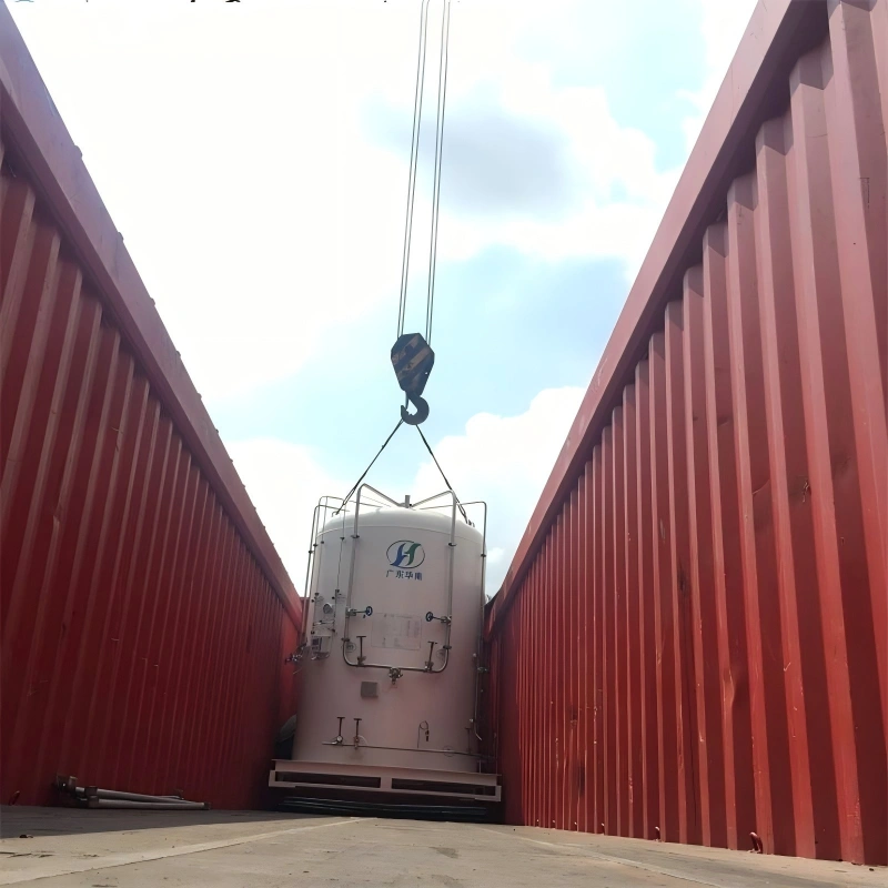 A large white industrial tank being carefully lowered by crane into a red shipping container, demonstrating precise loading operations for heavy machinery transport.