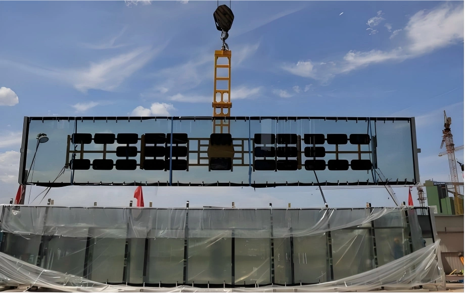 Specialized lifting equipment hoisting a large glass curtain wall section, highlighting stability and securement during the installation and transport process.