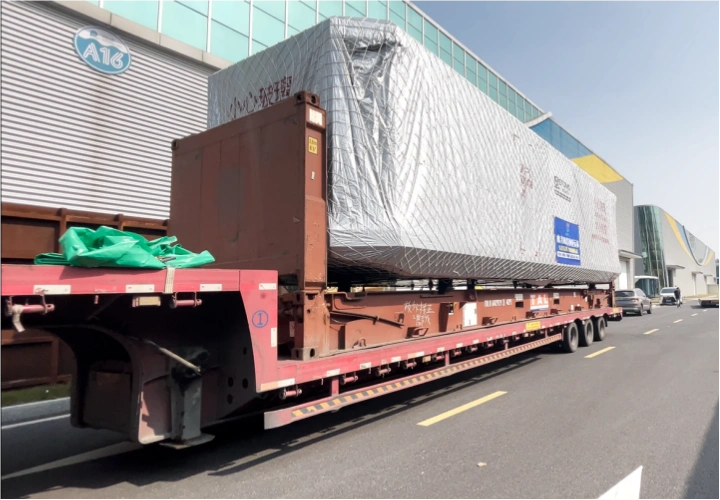 Rear perspective of a large, wrapped space capsule cabin secured on a flatbed trailer, highlighting its oversized dimensions for export logistics
