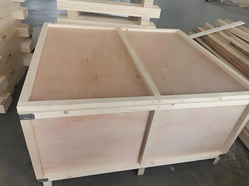 Close-up of a custom-built wooden crate base featuring reinforced skids and corner brackets, designed to support heavy industrial equipment during transport.