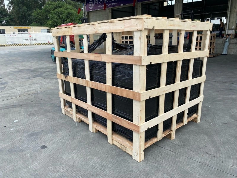 Side view of a tall wooden export crate with diagonal cross-bracing and shrink-wrapped contents, demonstrating load distribution and moisture protection