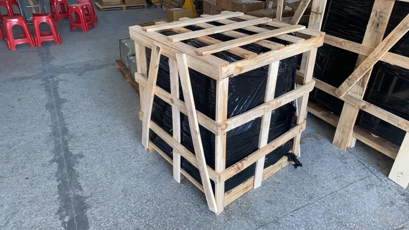 A sturdy wooden crate featuring diagonal bracing and black plastic wrapping inside, designed for heavy machinery export and moisture protection during ocean freight.