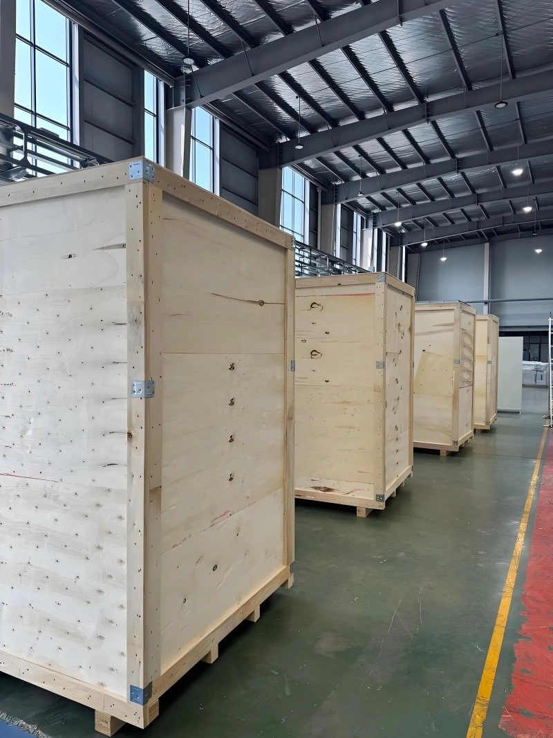 Multiple large wooden crates lined up in a modern factory facility, showcasing mass production capability and readiness for international shipping of precision machinery.