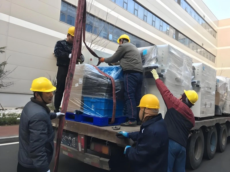 A team of movers securing palletized industrial equipment with heavy-duty straps on a transport truck, ensuring stability and safety for long-distance logistics.