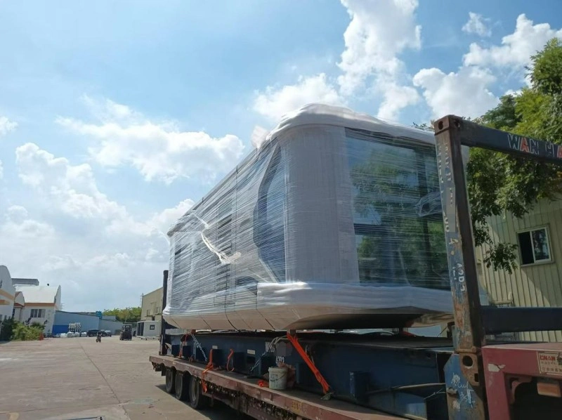 A large prefabricated space cabin module wrapped in protective plastic and secured with orange straps on a flatbed trailer, ready for relocation.