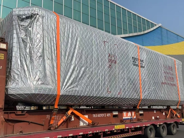Close-up view of a space capsule cabin wrapped in protective material and secured with orange lashing straps for safe transportation