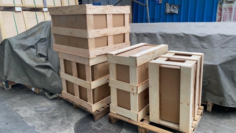 Multiple wooden crates with plywood lining and pallet bases stacked near a shipping container, demonstrating efficient space utilization and secure packaging for export logistics.