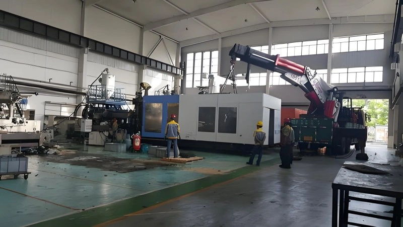 A large packaged industrial unit being lifted by crane through a building opening, demonstrating careful handling of sensitive equipment during installation or relocation.