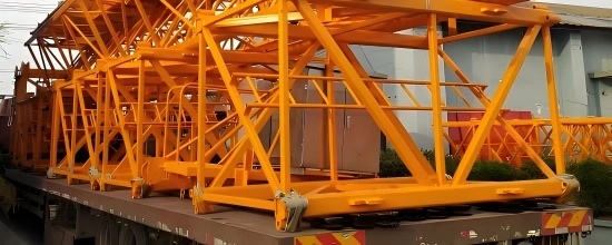Heavy-duty truck loaded with yellow lattice boom sections and steel framework, secured for road transport as part of an oversized logistics solution.