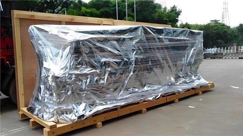 Industrial equipment fully wrapped in reflective aluminum foil barrier film, sealed tightly around a wooden pallet base, demonstrating advanced moisture and corrosion prevention for export shipping.