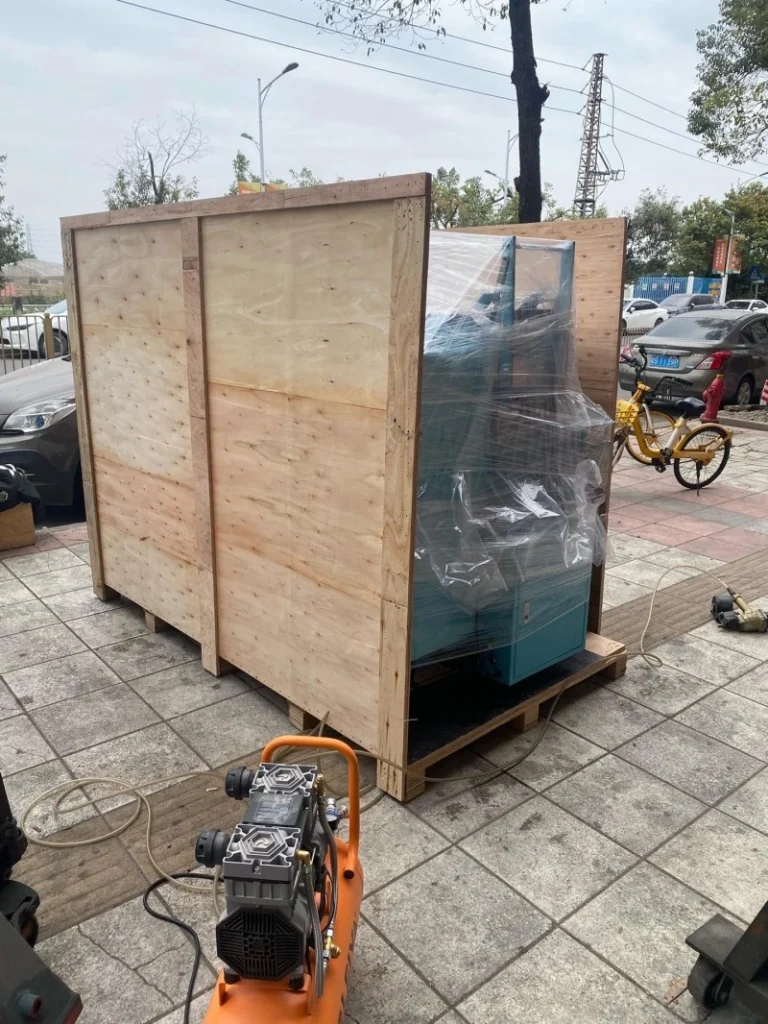 Industrial machine wrapped in plastic film inside a partially open plywood crate, demonstrating vacuum sealing and moisture barrier protection for sea freight