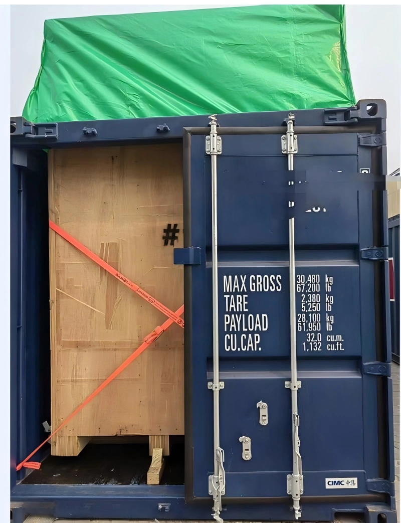 Inside view of an open top container showing a large wooden crate secured with orange lashing straps, with container door open and weight specs visible